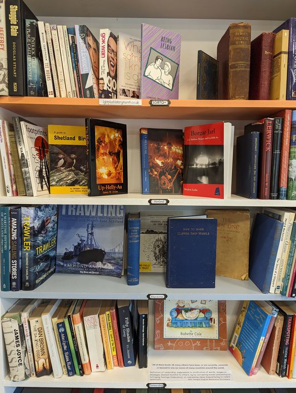 Books displayed on four shelves, respectively labelled LGBT+ history month, Shetland, maritime, and censorship